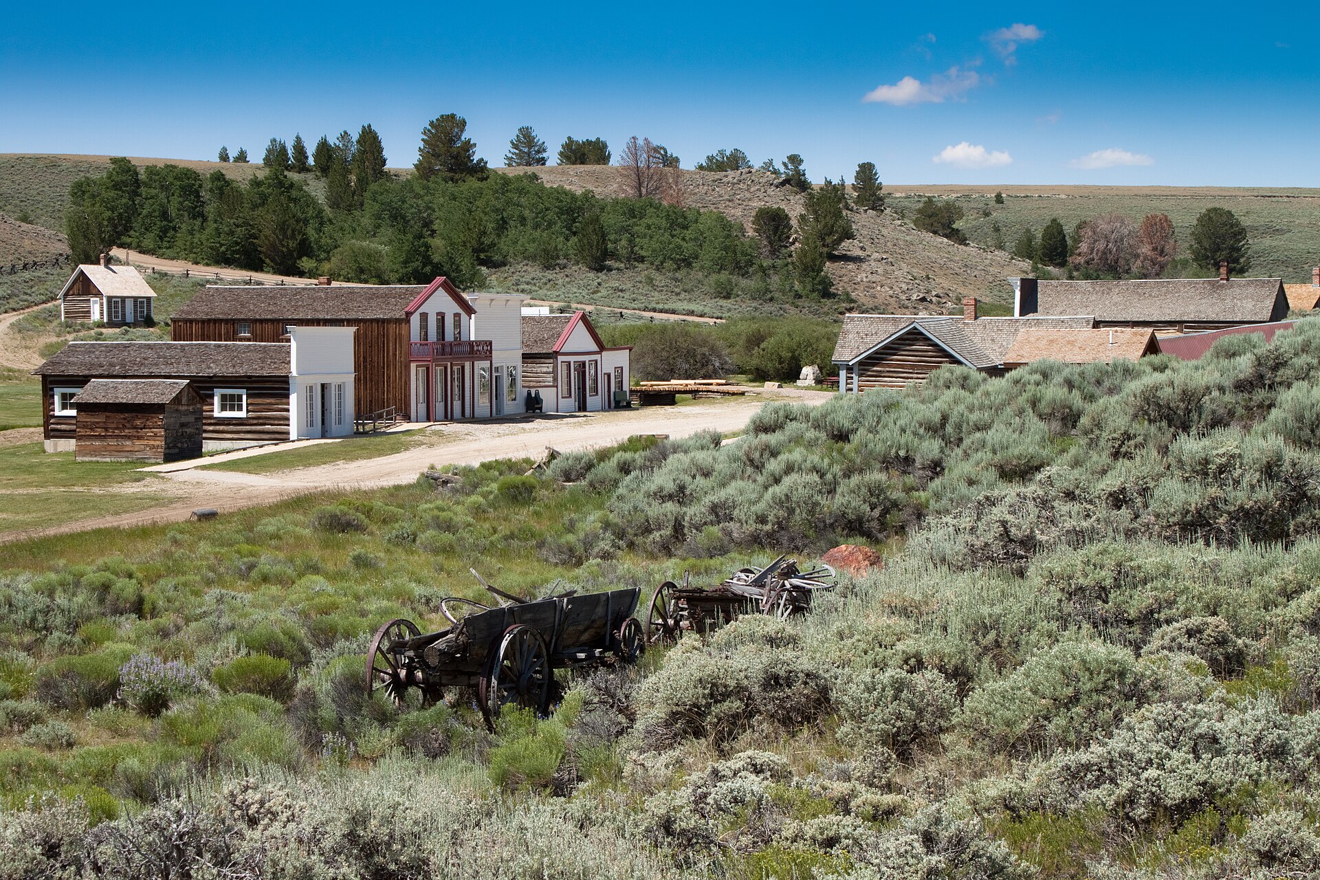 Restored frontier buildings of South Pass City State Historic Site, Wyoming, with original 1860s wooden storefronts under a high-altitude blue sky.