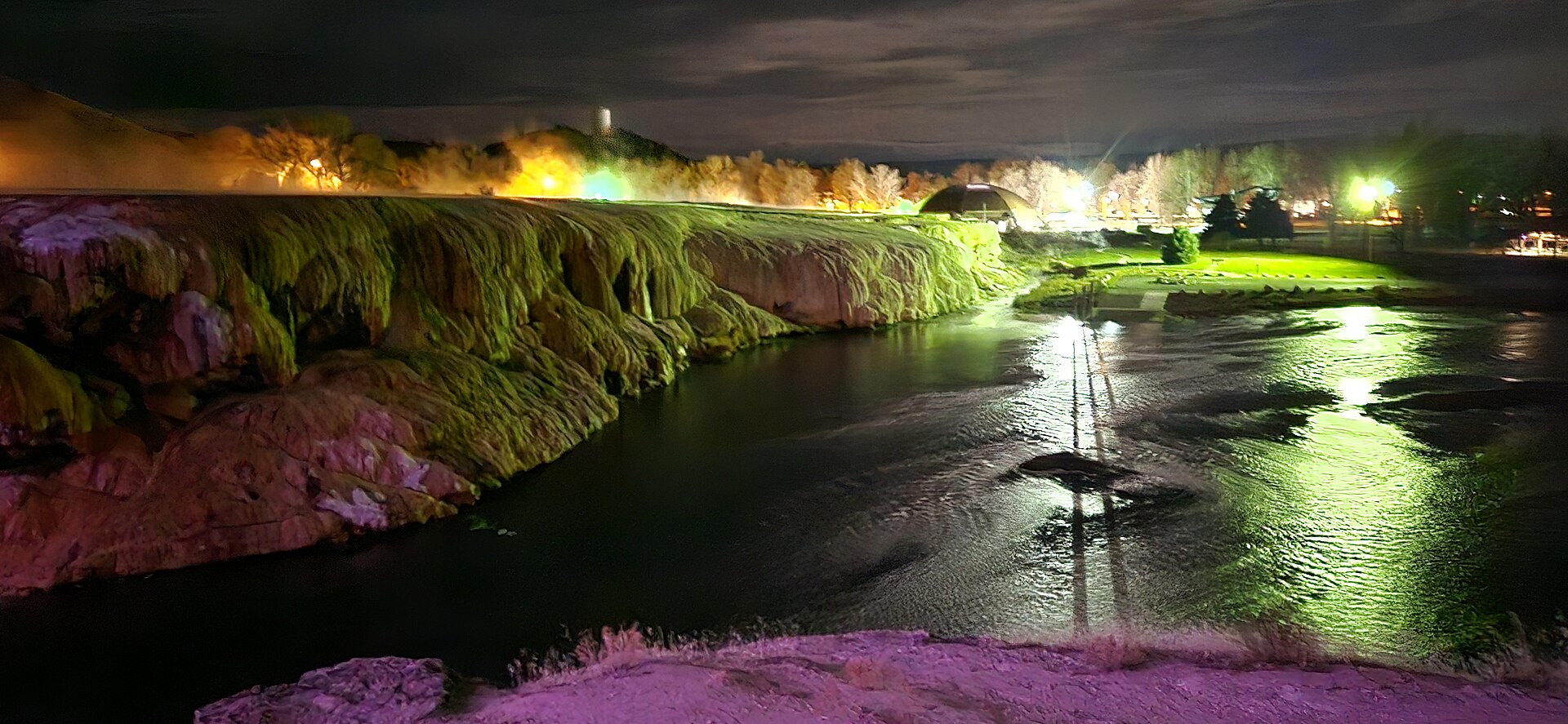 Steam rising from terraced mineral pools at Hot Springs State Park in Thermopolis, Wyoming, with the limestone-stained terraces in shades of orange, white, and pale green.