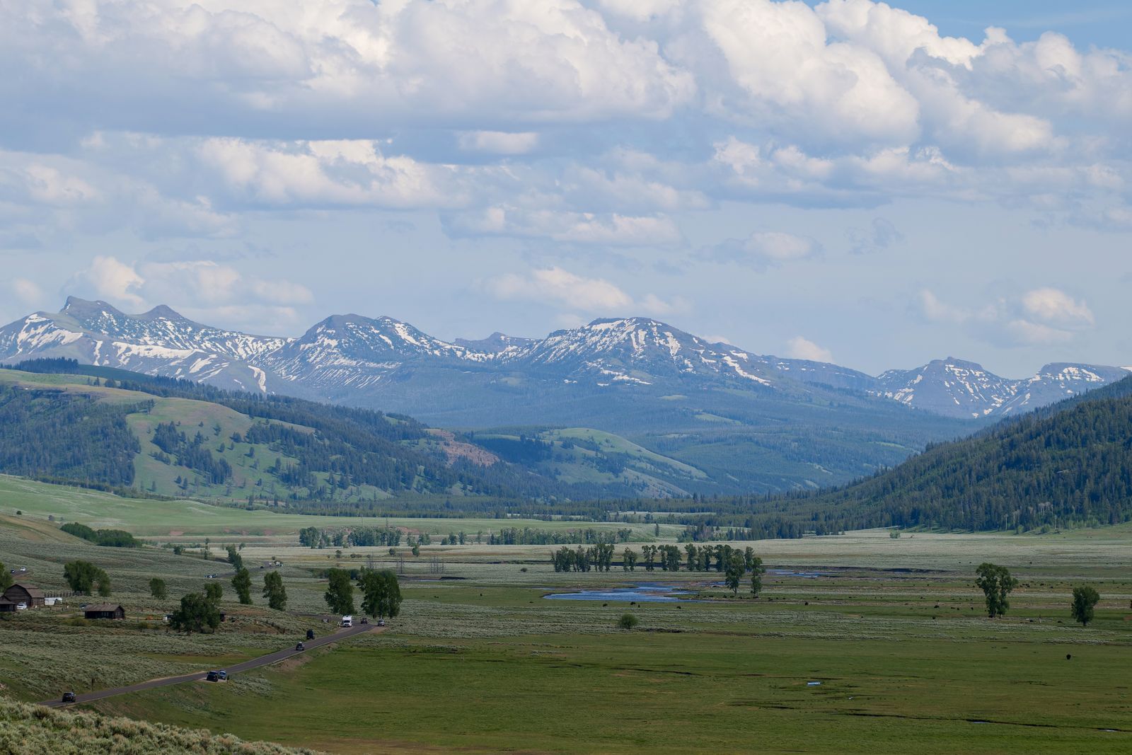 Two-lane mountain road with wide vista opening to the horizon.