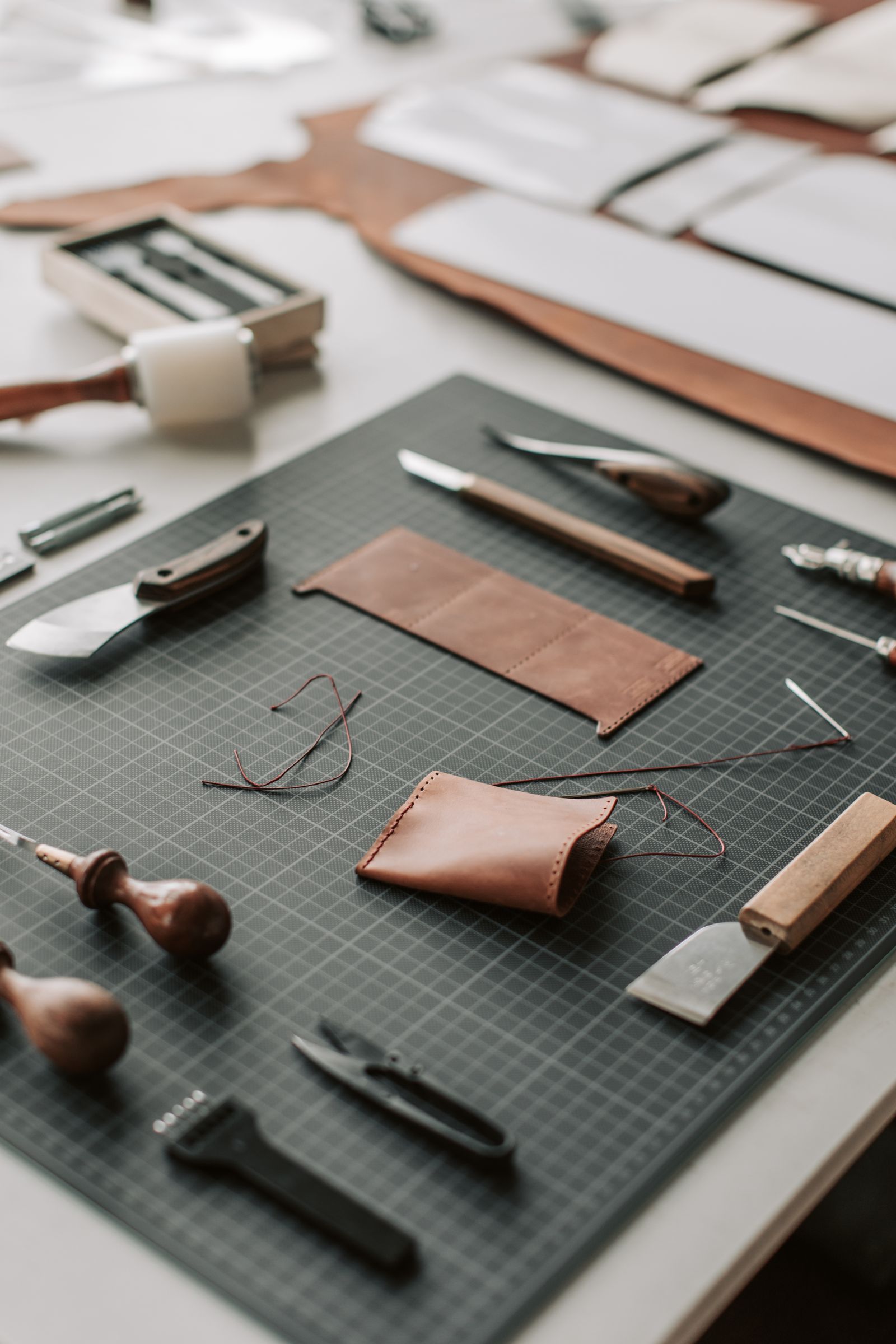 Close-up of leather tools and a partially-tooled piece on a workbench.