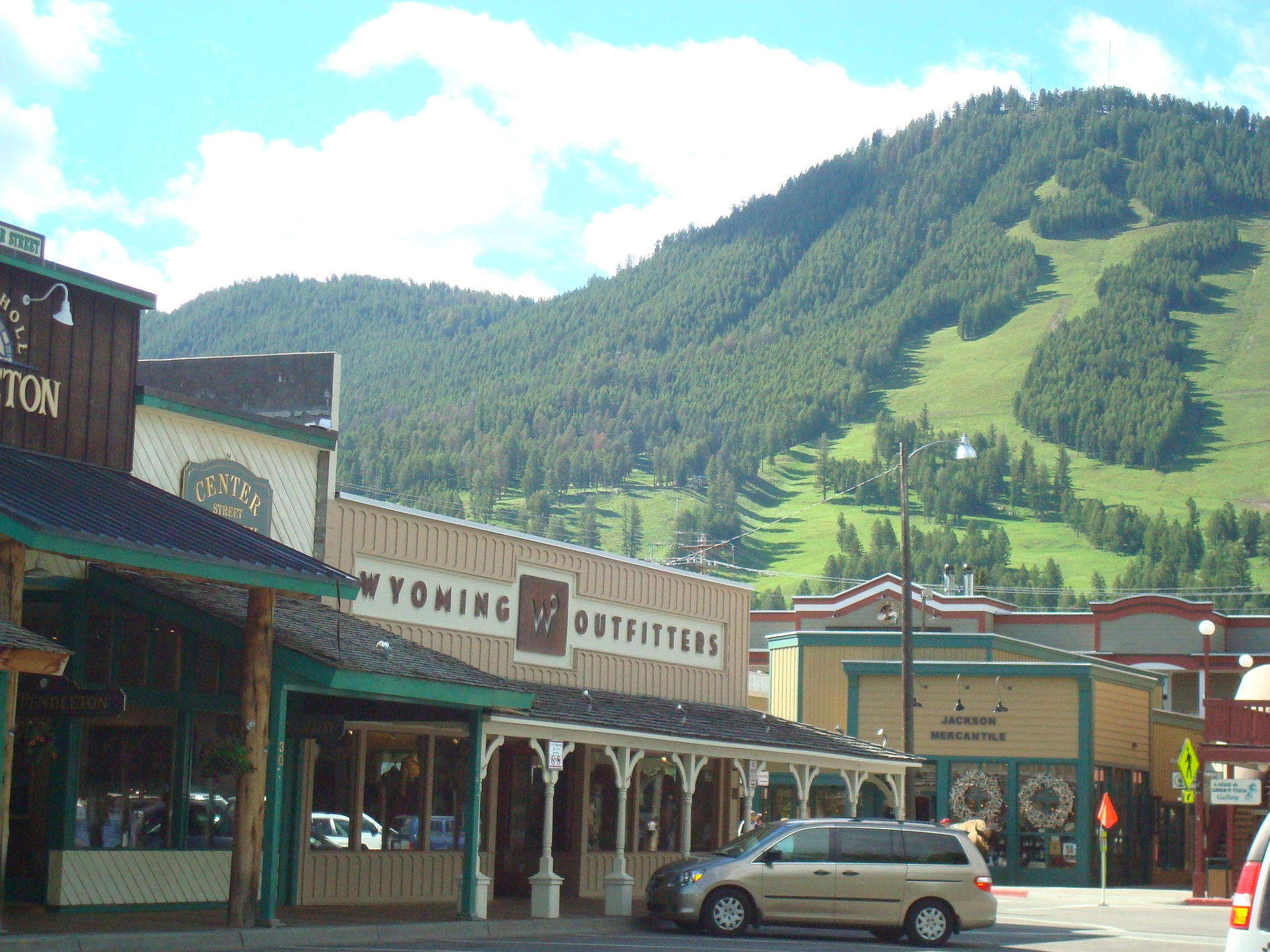 Jackson Town Square in Jackson, Wyoming, with the famous elk antler arches at the corner and the Tetons visible in the distance behind the storefronts.
