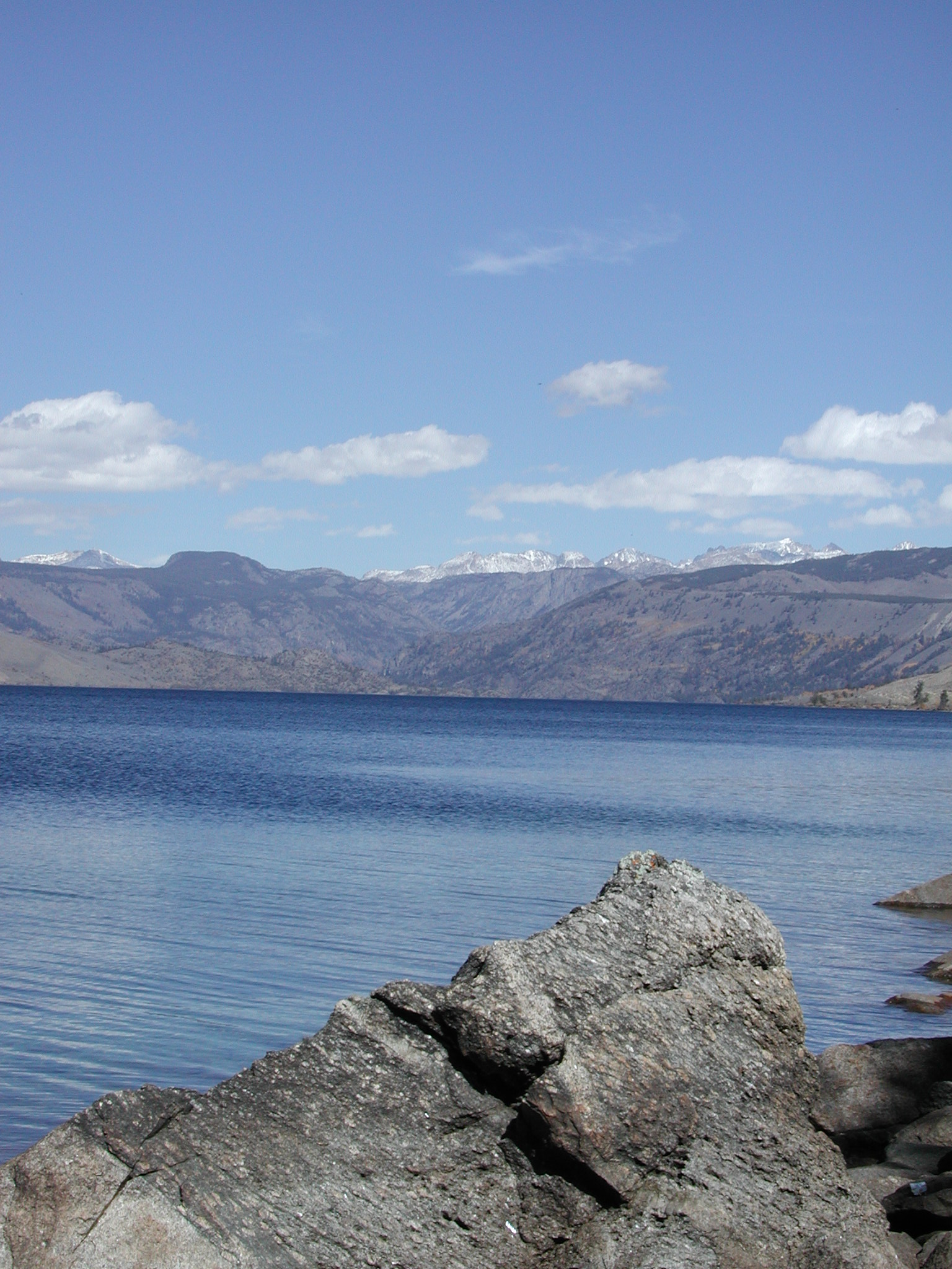 Fremont Lake near Pinedale, Wyoming, with the snow-capped Wind River Range rising directly from the lake's western shore under a clear blue sky.