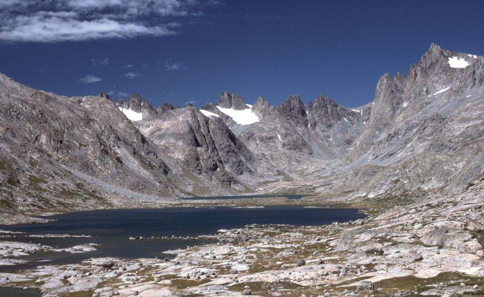 Titcomb Lakes basin in the Wind River Range, with granite peaks rising above two alpine lakes under a high cloud-streaked sky.